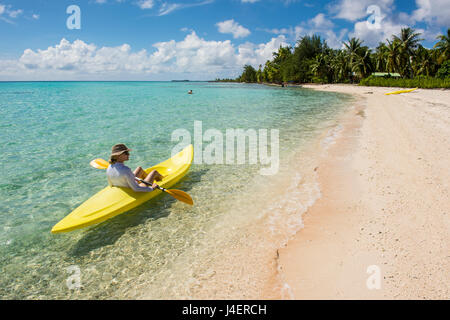 Donna kayak nelle acque turchesi di Tikehau, Tuamotus, Polinesia francese, Pacific Foto Stock