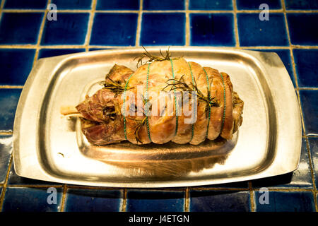 Arrosto di agnello avvolto in stringa appena fuori del forno su una cucina piastrellata counter Foto Stock