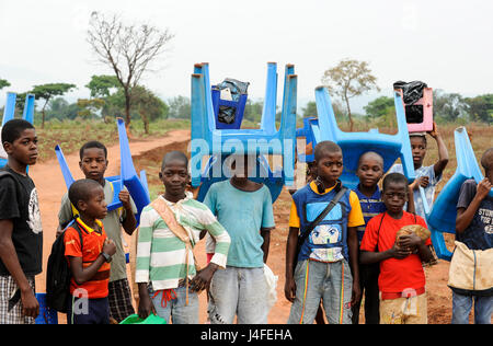 ANGOLA, Kwanza Sul, villaggio Kassombo, i bambini sulla strada per la scuola, ogni bambino deve portare la propria sedia in plastica come le scuole in cattivo stato a causa della guerra civile e la corruzione, i ricavi da olio ricco Angola sembra non raggiungere i villaggi / ANGOLA Kwanza Sul, Dorf Kassombo, Kinder mit Plastikstuehlen auf dem Weg zur Schule durch Felder des Dorfes, da die Schulen durch den Buergerkrieg zerstoert und ohne Inventar sind, muss jedes tipo seinen Plastik Stuhl mitbringen Foto Stock