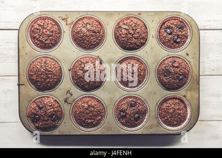 Crusca di cioccolato muffin con ciliegie, nella vecchia, grunge cercando, stagno vassoio, vista dall'alto Foto Stock