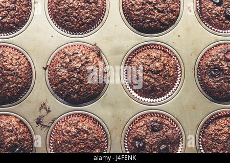 Crusca di cioccolato muffin con ciliegie, nella vecchia, grunge cercando, stagno vassoio, vista dall'alto Foto Stock