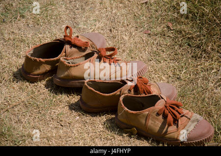 Danneggiato e vecchio brown sneakers studente sul terreno del giardino all'aperto Foto Stock