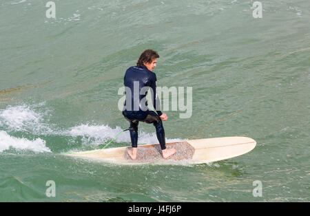 Surfer cavalcare un onda godendo il surf su una bella giornata di sole a Bournemouth Beach su lunedì festivo nel maggio - Bournemouth Dorset, Regno Unito Inghilterra Foto Stock