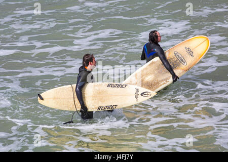 Surfers mantenendo le loro tavole da surf in mare dopo una buona sessione di navigazione su una bella giornata di sole a Bournemouth Beach su lunedì festivo nel Maggio Foto Stock