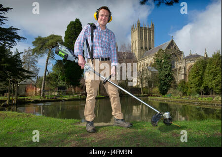 James cross, il capo giardiniere il taglio dell'erba nel palazzo del vescovo della Cattedrale di Wells (edificio in background) Foto Stock