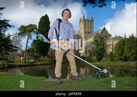 James cross, il capo giardiniere il taglio dell'erba nel palazzo del vescovo della Cattedrale di Wells (edificio in background) Foto Stock