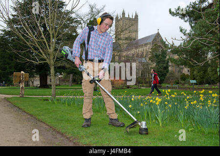 James cross, il capo giardiniere il taglio dell'erba nel palazzo del vescovo della Cattedrale di Wells (edificio in background) Foto Stock