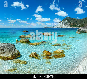 Spiaggia di Petani summer view con grosse pietre in acqua e il profondo blu del cielo nuvoloso (Cefalonia, Grecia). Foto Stock