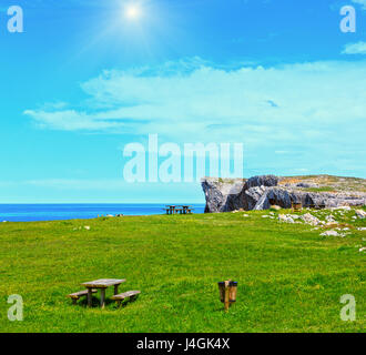 Luogo di riposo (tavola con panche) sulla fioritura estiva sunshiny costa vicino Camango, nelle Asturie (Spagna). Due colpi stitch immagine. Foto Stock