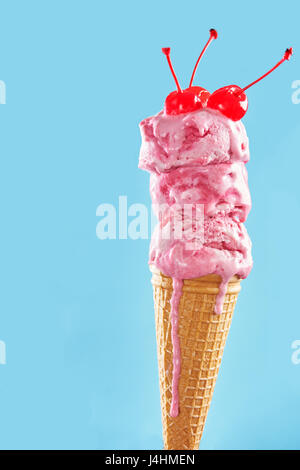 La fusione di cono gelato decorato con coctail ciliegia sulla backround blu Foto Stock