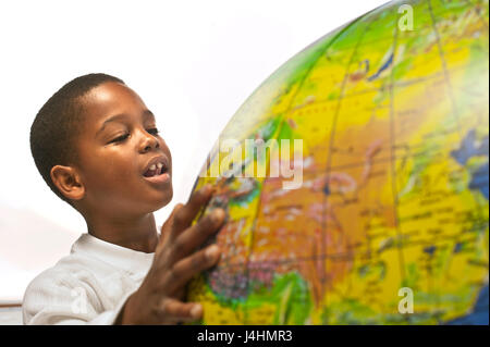 Un felice sana African American boy guardando un globo gonfiabile su uno sfondo bianco. Il globo è soft focus in primo piano e mostra la Cina Foto Stock