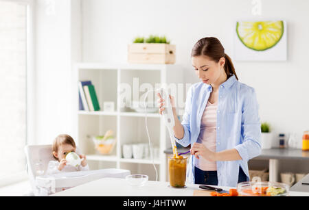 Madre con blender la cottura di cibo per bambini a casa Foto Stock