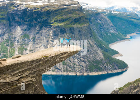 Matura in posa sul Trolltunga. Felice l'uomo e la donna godere del bellissimo lago e buone condizioni meteorologiche in Norvegia. Foto Stock