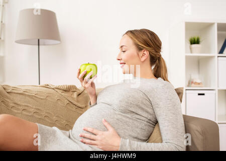 Felice donna incinta con mela verde Foto Stock