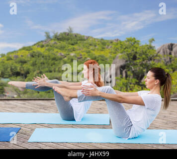 Donne che fanno yoga a mezza barca pongono all'aperto Foto Stock