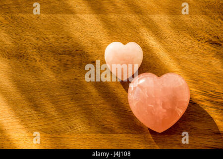 2 X quarzo rosa a forma di cuore laici piatta sul legno naturale. Foto Stock