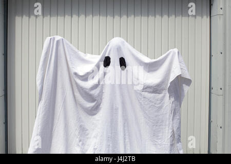 Un fantasma bianco di fronte a una porta di garage Foto Stock