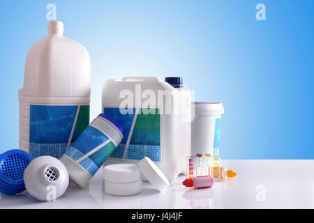 Ai prodotti chimici di pulizia per acqua di piscina sul tavolo bianco e blu. Composizione orizzontale. Vista frontale Foto Stock