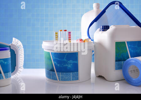 Ai prodotti chimici di pulizia per acqua di piscina sul tavolo bianco e blu sullo sfondo di mosaico. Composizione orizzontale. Vista frontale Foto Stock
