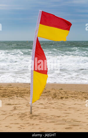 Rosso e giallo di flag che indicano una zona sicura per nuotare al mare sulla spiaggia di Bournemouth nel mese di aprile Foto Stock