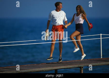 Bridge, giovane, mano nella mano, fuso al di fuori, pontile, jetty, giovane, hop, jump, crack, felicemente, felicemente, allegramente, allegria, divertente, gioia, vacanze, tempo libero, mare Foto Stock