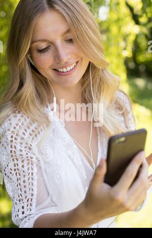 Giovane donna ascoltare musica sullo smartphone. Foto Stock