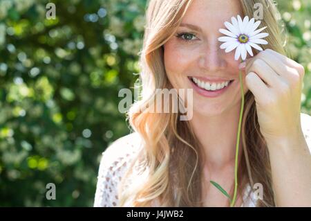 Giovane donna Margherita di contenimento nella parte anteriore dell'occhio. Foto Stock