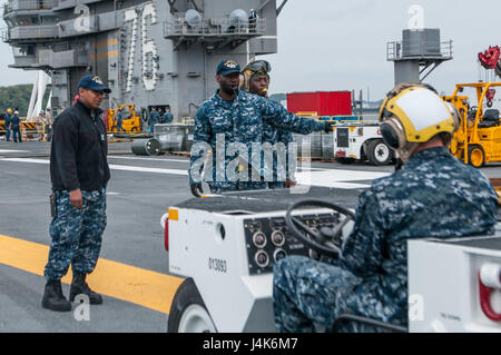 170426-N-PF593-045 Yokosuka, Giappone (26 aprile 2017) dell'aviazione di Boatswain Mate (manipolazione) 2a classe Emmanuel Gedeon, da Miami, dirige il conducente del trattore durante un movimento di aerei sul ponte di volo della Marina è solo avanti-aeromobili impiegati carrie, USS Ronald Reagan (CVN 76). La aviation boatswain compagni spostato il velivolo come corsi di formazione per le operazioni di volo. Ronald Reagan, il portabandiera del Carrier Strike gruppo 5, fornisce un combattimento-pronto forza che protegge e difende la collettiva degli interessi marittimi dei suoi alleati e partner in Indo-Asia-regione del Pacifico. (U.S. Foto di Marina di Massa Co Foto Stock