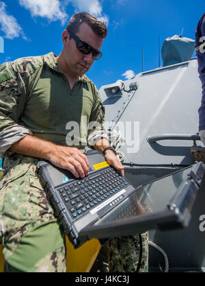 Un marinaio assegnato per l'eliminazione degli ordigni esplosivi unità mobile 5 (EODMU5) plotone 142 utilizza un laptop a bordo di una costiera gruppo fluviale 1 Distacco Guam MK VI imbarcazione di pattuglia per ricevere aggiornamenti di stato da un unmanned veicolo sottomarino al largo di Saipan Maggio 9, 2017. EODMU5 sta attualmente testando la sua capacità di distribuire beni da varie piattaforme, compresi gli elicotteri e motovedette per aumentare la sua interoperabilità adattativo. EODMU5 conduce la mia contromisure, esplosivi improvvisati operazioni del dispositivo, rende sicuro rischi di esplosione e disarma underwater esplosivi come mine. (U.S. Navy Co Foto Stock