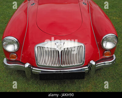 Dettaglio del rosso lucido classic MG veicolo che mostra le ali anteriori cofano chrome calandra proiettori & distintivo al classic car show in Cumbria, England Regno Unito Foto Stock