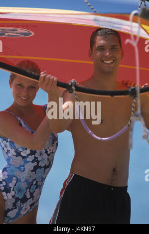 Spiaggia, mare, giovane, felicemente, vela surf, portare con sé la spiaggia sabbiosa, estate, vacanze, tempo libero, lifestyle, hobby, navigare in internet, wind surf, vela, allegria, felicemente, divertente, insieme, giovane, cade nell'amore, tuning, positivamente, allegramente Foto Stock