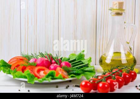 Cetrioli, Rafano, pomodori ciliegia, olio d'oliva, erbe e spezie sul vecchio bianco sullo sfondo di legno. Impostare i cibi sani. Ingredienti per insalata. Foto Stock