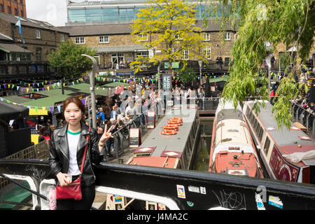 Un giovane turista asiatico posa per una foto e mostra due dita vicino a Camden Lock, Camden Market a NW1, Londra, Regno Unito Foto Stock