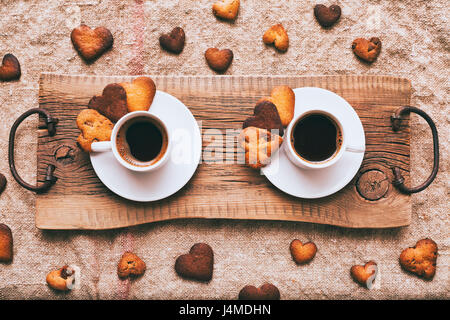 Il caffè e il cuore-forma di cookie sul vassoio in legno Foto Stock