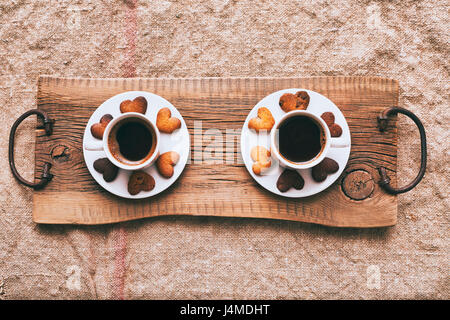 Il caffè e il cuore-forma di cookie sul vassoio in legno Foto Stock