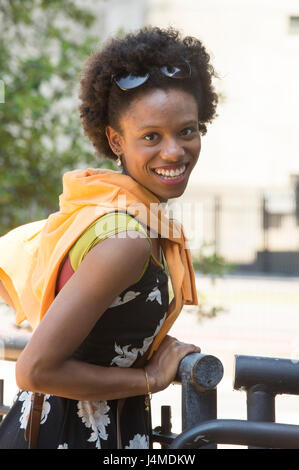 Ritratto di sorridere americano africano donna appoggiata sul parapetto Foto Stock