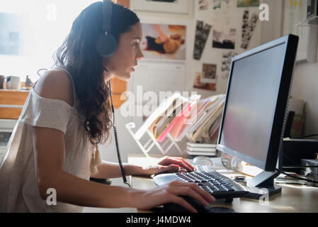 Donna ispanica ascolto di computer con le cuffie Foto Stock