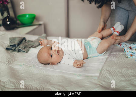 Madre caucasica cambiando pannolino del neonato figlio sul letto Foto Stock