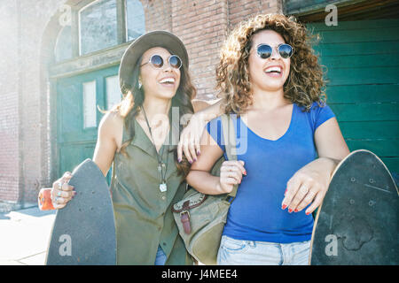 Razza mista donne azienda di skateboard in città Foto Stock