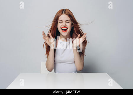 Emozionato Caucasian donna seduta al tavolo di vento Foto Stock