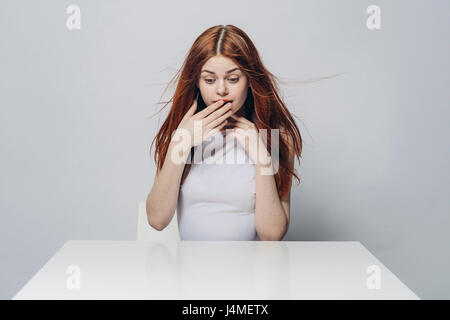 Sorpreso Caucasian donna seduta al tavolo di vento Foto Stock