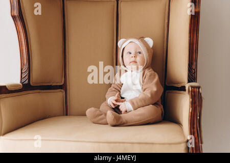 Caucasian bimbo seduto in poltrona indossando il costume orso Foto Stock