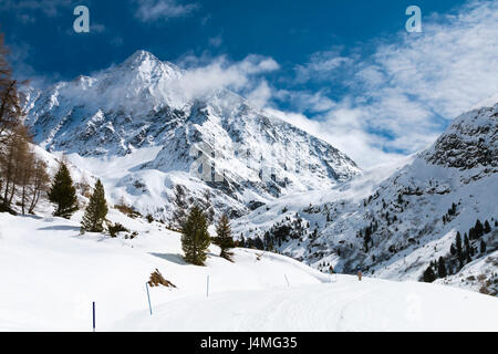 Vista del 3500m alto Schrankogel nell'Oetztal, Austria con paesaggi innevati e cielo blu, una strada innevata in primo piano. Foto Stock