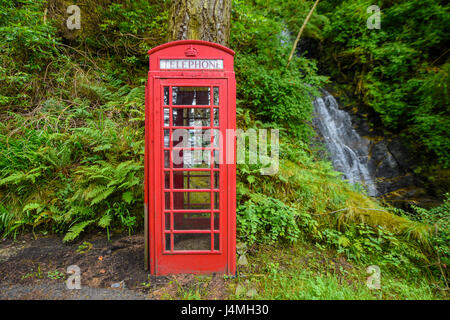 Telefono rosso box nella foresta accanto ad una cascata. La Scozia, Regno Unito Foto Stock