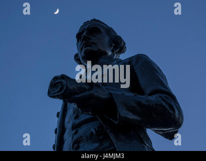 Una mezzaluna sopra la statua del capitano James Cook al porto di Victoria, British Columbia, Canada. Foto Stock