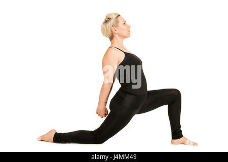 Seitliche Ganzkörper-Ansicht einer jungen Frau auf weißen Hintergrund im schwarzen Sportdress eine variante der Yoga-Übung Heldenstellung (Anjaneyasa Foto Stock