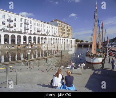 Germania, Hamburg Alster portici, canale Alster, veliero, donne, sedersi, vista posteriore in Europa, in nord Germania, città anseatica, paese, città, parte della città, città quarto, City Centre, Municipio di mercato, Jungfernstieg, il flusso dall'Alster, nave, pontile, cigni, palazzi, architettura, portici, negozi, caffetterie Foto Stock