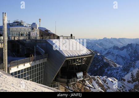 In Germania, in Baviera, Zugspitze, vette, stazione meteo, funivia, visualizzare paesaggio di montagna, Alta Baviera, Werdenfels, gamma di Wetterstein, Zugspitze vertice, vertice, cima, stazione di vertice, stazione meteo, funivia, vertice terrazza, terrazza, persona, vertice di croce, la croce, neve, sole, panorama di montagna, montagne delle Alpi, cielo blu, inverno, Foto Stock