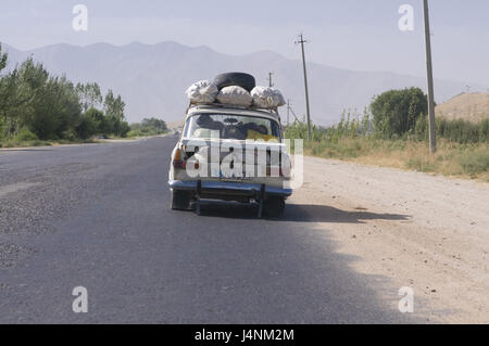 Caricate completamente auto va sulla strada di campagna, Shakrisabz, Uzbekistan, Foto Stock