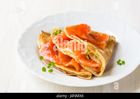 Crepes con salmone affumicato su una piastra bianca Foto Stock